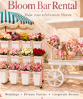 Danaya’s Flowers Bloom Bar setup with pink flower rack, white bouquet cart and striped umbrella.