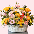 Luxury pastel flower basket with yellow and peach roses, pink lisianthus, gerbera and chrysanthemums arranged in a white wicker basket – Abu Dhabi florist