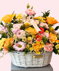 Luxury pastel flower basket with yellow and peach roses, pink lisianthus, gerbera and chrysanthemums arranged in a white wicker basket – Abu Dhabi florist