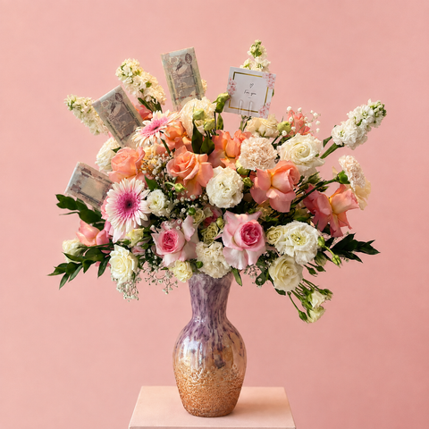 Luxury pink and white flower arrangement with UAE dirham notes in a pink glass vase.