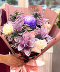 Bouquet of flowers with currency notes wrapped in brown paper, held by a person.
