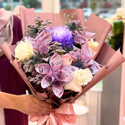 Bouquet of flowers with currency notes wrapped in brown paper, held by a person.