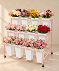 Pink three-tier flower display rack with twelve white buckets styled with colourful fresh flowers.