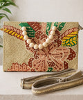 Woven clutch bag with floral design and wooden beads on a neutral background