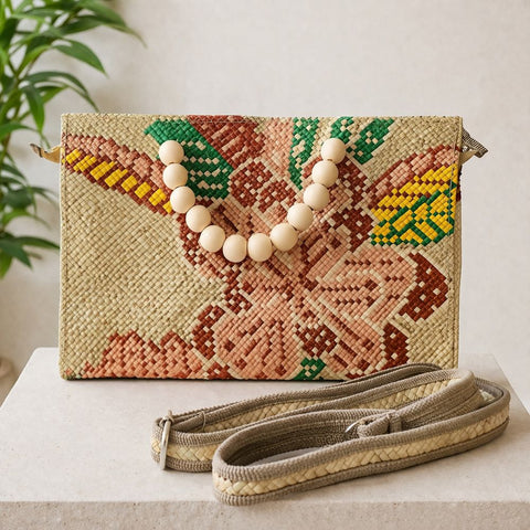 Woven clutch bag with floral design and wooden beads on a neutral background