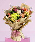 Bouquet of flowers wrapped in newspaper with a pink ribbon on a pink background