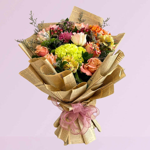 Bouquet of flowers wrapped in newspaper wrap with a pink bow on a light purple background