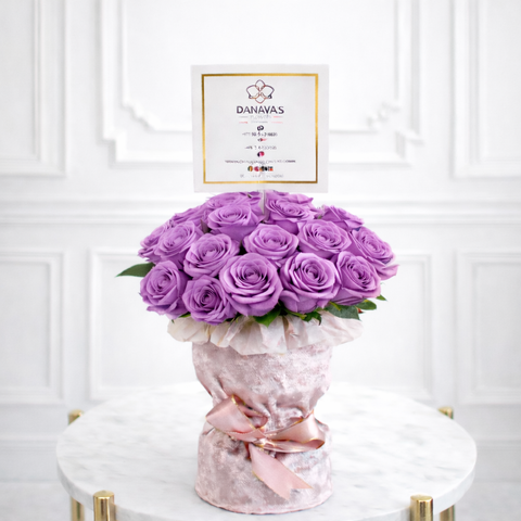 Bouquet of purple roses in a decorative vase with a 'DANAYAS' card on a white background