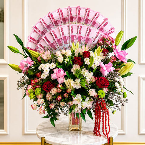 Luxury money flower arrangement with pink roses, red roses, lilies, and a fan of UAE banknotes in a glass vase by Danaya’s Flowers Abu Dhabi.