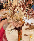 Neutral-toned dried flower arrangement in a decorative white vase.