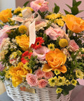 Bouquet of colorful flowers in a white basket with a pink background