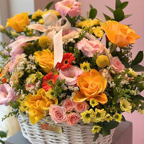 Bouquet of colorful flowers in a white basket with a pink background