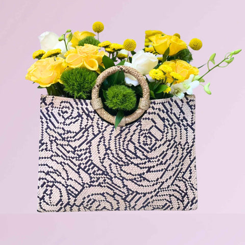 Patterned handmade tote bag with floral arrangement on a light pink background