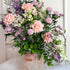 Bouquet of flowers in a pink vase on a white surface