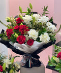 Bouquet of red and white flowers on a stand with a pink background