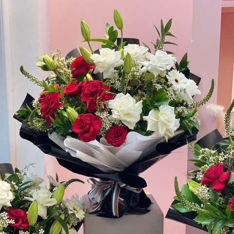 Bouquet of red and white flowers on a stand with a pink background