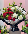 Bouquet of red and white flowers on a stand with a pink background