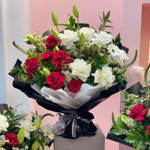 Bouquet of red and white flowers on a stand with a pink background