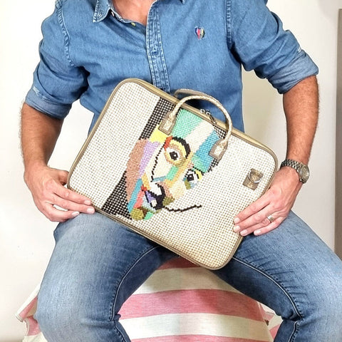 Person holding a decorative laptop bag with a colorful man design.