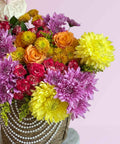 Colorful bouquet of flowers in a woven basket on a pink background