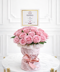 Bouquet of pink roses in a decorative vase with a 'DANAYAS' card on a white background