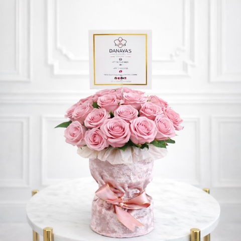 Bouquet of pink roses in a decorative vase with a 'DANAYAS' card on a white background