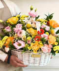 Person holding a colorful flower basket with 'Danaya's Flowers' branding.