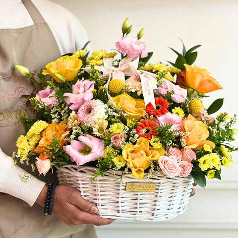 Person holding a colorful flower basket with 'Danaya's Flowers' branding.