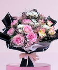 Blushing Grace Bouquet with pink roses, spray roses, and pastel blooms wrapped in black and white with a pink ribbon – luxury flower bouquet Abu Dhabi