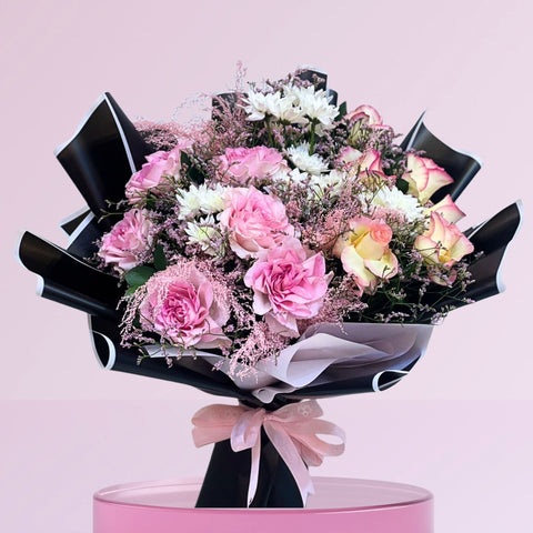 Blushing Grace Bouquet with pink roses, spray roses, and pastel blooms wrapped in black and white with a pink ribbon – luxury flower bouquet Abu Dhabi