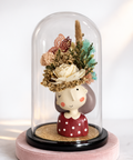 Decorative figure with floral head under a glass dome on a white background