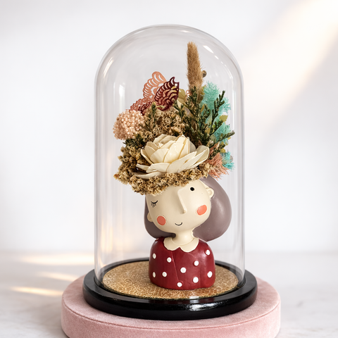 Decorative figure with floral head under a glass dome on a white background
