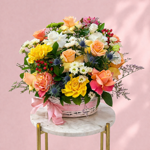Colorful flower arrangement in a basket on a marble table with a pink background, abu dhabi delivery
