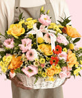 Person holding a basket of colorful flowers against a pink background