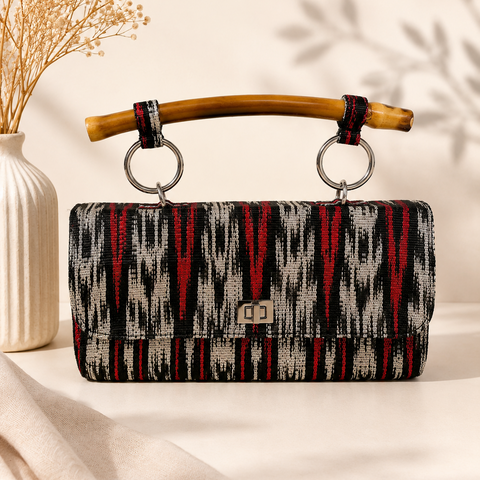 Handwoven Filipino tinalak clutch bag with natural bamboo handle and silver twist-lock closure.