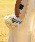 Person holding a bouquet of flowers with a blurred natural background
