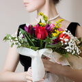 Bouquet of flowers held by a person with a neutral background